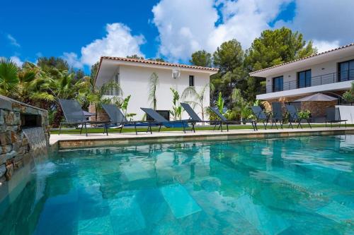 une piscine avec des chaises et une maison dans l'établissement Villa Romy - calme & piscine chauffée, à Sanary-sur-Mer