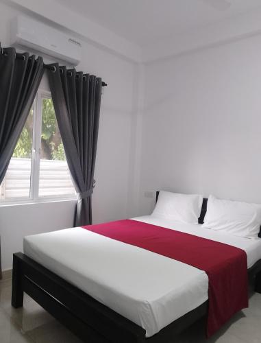 a bedroom with a large bed with a window at Laxsume Guest House Nilaveli in Nilaveli