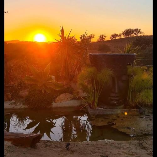 a sunset with a vase in front of a body of water at Herdade da Maceira in São Luis