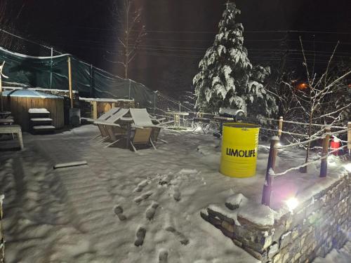a snow covered yard with a christmas tree and a yellow barrel at Casa Edenland Doftana in Trăisteni