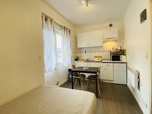 Cette petite chambre comprend un lit et une cuisine avec une table. dans l'établissement Le Perie, à Rodez