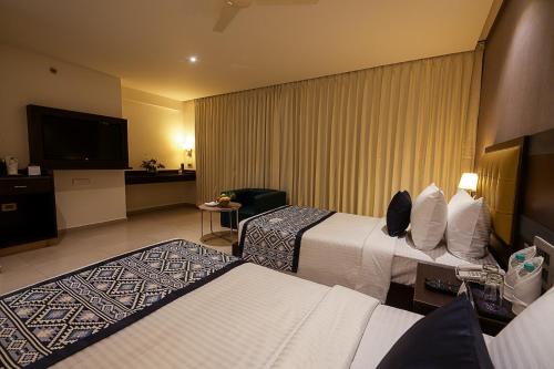 a hotel room with two beds and a flat screen tv at Grand Continent Malleshwaram A Sarovar Portico Affiliate Hotel in Bengaluru