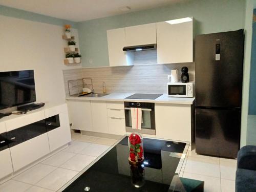 a kitchen with white cabinets and a black refrigerator at WIFI - PARKING - SUPERBE T3 SPACIEUX ET MODERNE!!!! in Saint-Denis