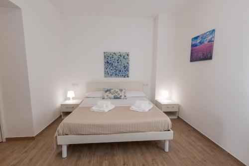 a white bedroom with a bed and two tables at A Casa di Amici Apartment in Giardini Naxos