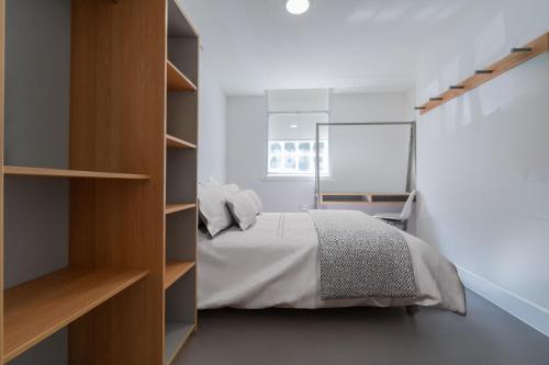 For Students Only Ensuite Bedrooms with Shared Kitchen and Studios at The Old Fire Station in Birmingham في برمنغهام: غرفة نوم مع سرير ورف كتاب
