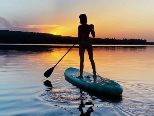 a woman standing on a paddle board in the water at NEW - The Surf Shack - on a lake near Amsterdam! in Vinkeveen
