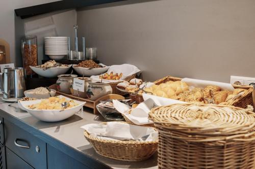 a counter with many baskets of bread and other foods at Helvetia Hotel Munich City Center in Munich