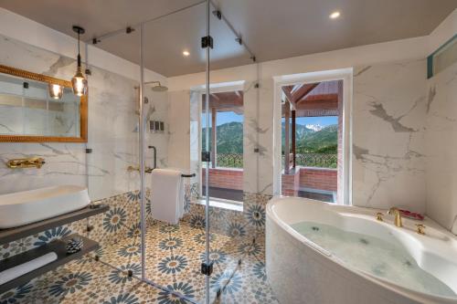 a bathroom with a tub and a glass shower at juSTa Birding Resort & Spa - Best Dhauladhar View Resort in Dharamshala