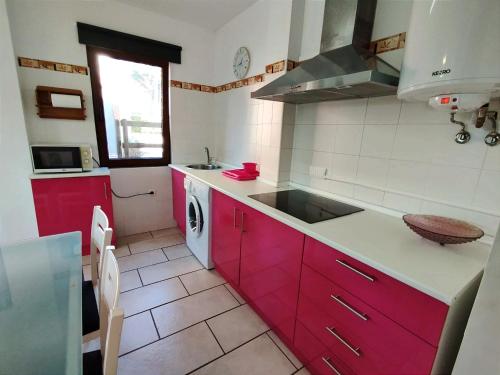 une cuisine avec des armoires rouges et un évier dans l'établissement Apartamentos Copi Villa de Suances, à Suances