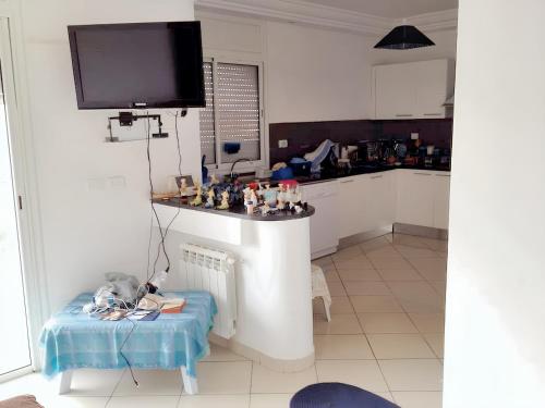a kitchen with a table and a tv on the wall at 2 bedrooms apartement at Hammamet 100 m away from the beach with sea view shared pool and balcony in Hammamet