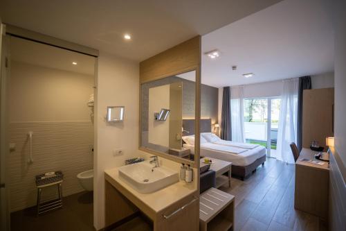 łazienka z umywalką, łóżkiem i lustrem w obiekcie Hotel Bellariva w mieście Riva del Garda