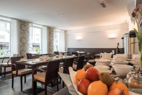 uma sala de jantar com mesas e cadeiras e frutas nos pratos em Helvetia Hotel Munich City Center em Munique