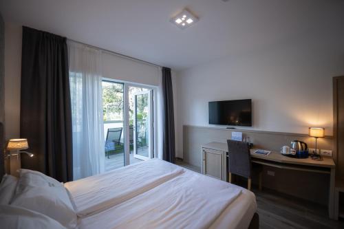 a hotel room with a bed and a desk and a window at Hotel Bellariva in Riva del Garda