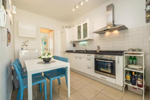 a kitchen with a white table and blue chairs at Central Ana Sutivan in Sutivan