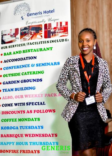 una mujer está parada frente a un cartel en Generis Hotel, en Nakuru