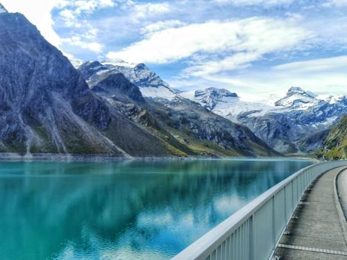 a bridge over a mountain lake with snow covered mountains at Villa Frieda mit Zell am See-Kaprun Summer Card in Zell am See