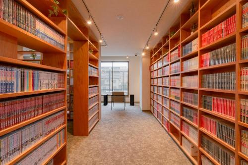 a library with wooden shelves filled with books at Matsumoto Tourist Hotel in Matsumoto