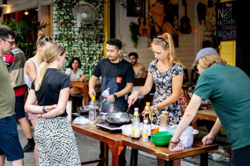 a group of people standing around a table preparing food at Back Home Backpackers in Bangkok