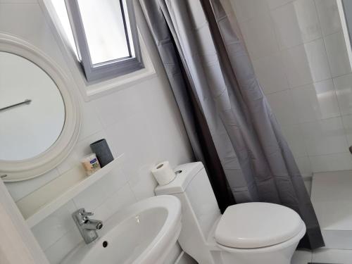 a bathroom with a toilet and a sink and a window at Paradise Gardens, sweet Apartment in Limassol