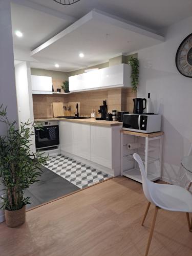 kuchnia z białymi szafkami, stołem i krzesłem w obiekcie Bel Appartement, Sélestat w mieście Sélestat