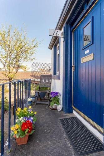 a blue house with a blue door and some flowers at McHoppity House - Crail in Crail