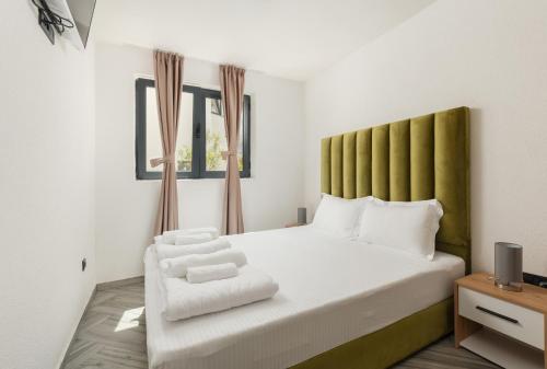 a bedroom with a white bed with a green headboard at Rajska dolina Budva in Budva