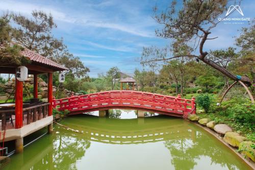 a red bridge over a pond in a garden at Quảng Ninh Gate Hotel & Resort in Bác Mã