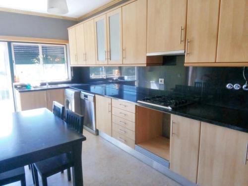 a kitchen with wooden cabinets and a black counter top at 2 bedrooms apartement with enclosed garden and wifi at Urqueira in Urqueira