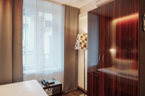 1 dormitorio con cama, ventana y lámpara en Helvetia Hotel Munich City Center en Múnich