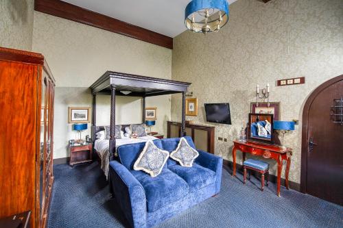 a bedroom with a bed and a blue couch at Langley Castle Hotel in Hexham