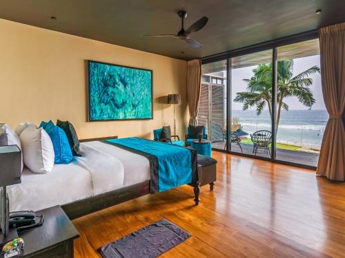 a bedroom with a bed with a view of the ocean at DORMERO Hotel Sri Lanka Hikkaduwa Beach in Hikkaduwa