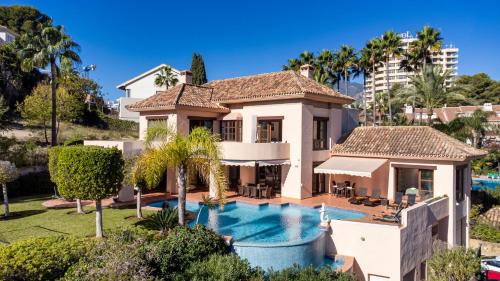 Villa con piscina frente a una casa en Luxury Villa Robledal By Mabiente - Views of the sea and the golf course, en Marbella