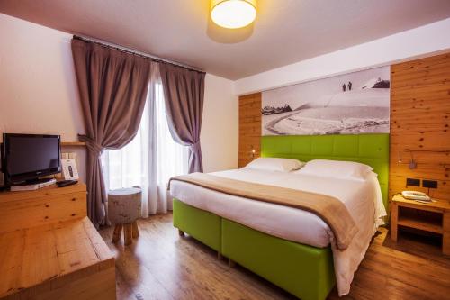 a bedroom with a large green bed and a television at Hotel Pilier D'Angle & Wellness in Courmayeur