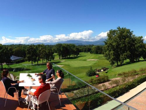 a group of people sitting at a table overlooking a golf course at Villaverde Hotel Spa&Golf Udine in Fagagna