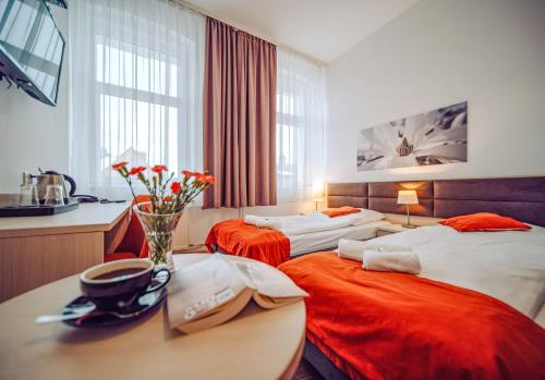 una habitación con 2 camas y una mesa con un jarrón de flores en Dobrzyński Resort Topaz, en Świeradów-Zdrój