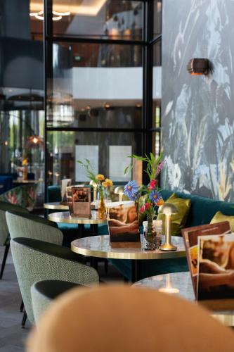 a row of tables and chairs with flowers on them at Hotel Van der Valk Maastricht in Maastricht