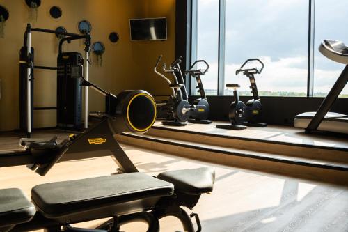 a gym with a row of exercise equipment and windows at Hotel Van der Valk Maastricht in Maastricht