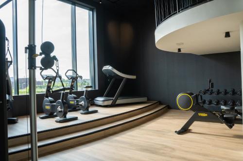 a gym with exercise equipment and a large window at Hotel Van der Valk Maastricht in Maastricht