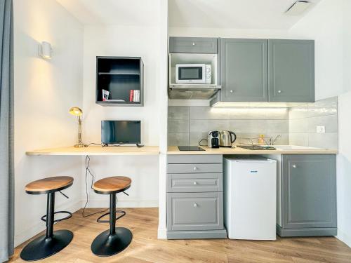 une cuisine avec deux tabourets et un comptoir dans l'établissement Le Victor Hugo, à Périgueux