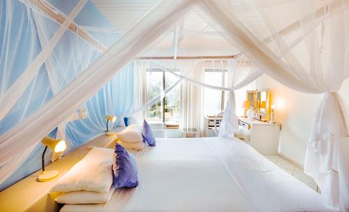 Flamboyant Diani Beach في شاطئ دياني: غرفة نوم بسرير ابيض بسقف ازرق