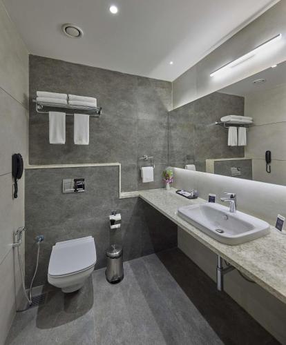 a bathroom with a white toilet and a sink at Grand Continent Hosur A Sarovar Portico Affiliate Hotel in Hosūr