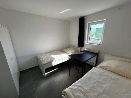 a room with two beds and a desk and a window at Monteurunterkunft Schwaig in Schwaig bei Nürnberg
