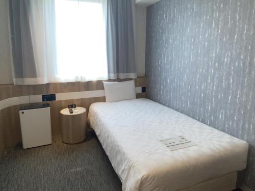 um pequeno quarto com uma cama e uma janela em Henn na Hotel Komatsu Ekimae em Komatsu