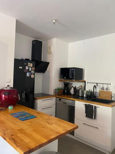 Il comprend une cuisine équipée d'un réfrigérateur noir et d'une table en bois. dans l'établissement Appartement charmant à 10 minutes des plages, à Châteauneuf-les-Martigues