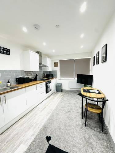 a kitchen with white cabinets and a table in it at 202 Grosvenor House in Wakefield