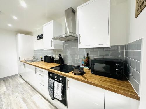 a kitchen with white cabinets and a black microwave at 202 Grosvenor House in Wakefield