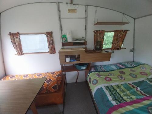 Cette petite chambre comprend un lit, un bureau et une table. dans l'établissement CARAVANE Vintage, à Beulotte-Saint-Laurent