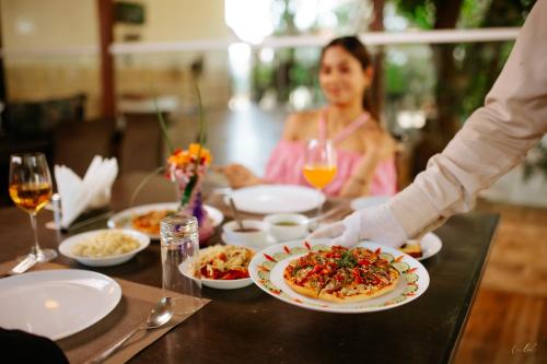 a woman sitting at a table with a plate of food at Daksh Resort And Amusement Park in Sasan Gir