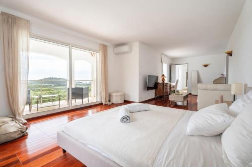 - une chambre avec un grand lit blanc et une grande fenêtre dans l'établissement Villa vue mer et pinède, à Bandol