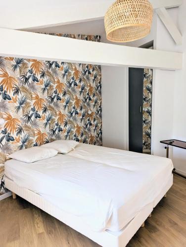 - une chambre avec un lit blanc et un papier peint tropical dans l'établissement Ile d oléron Vertbois, Villa Bois Piscine et mer, à Dolus-d'Oléron